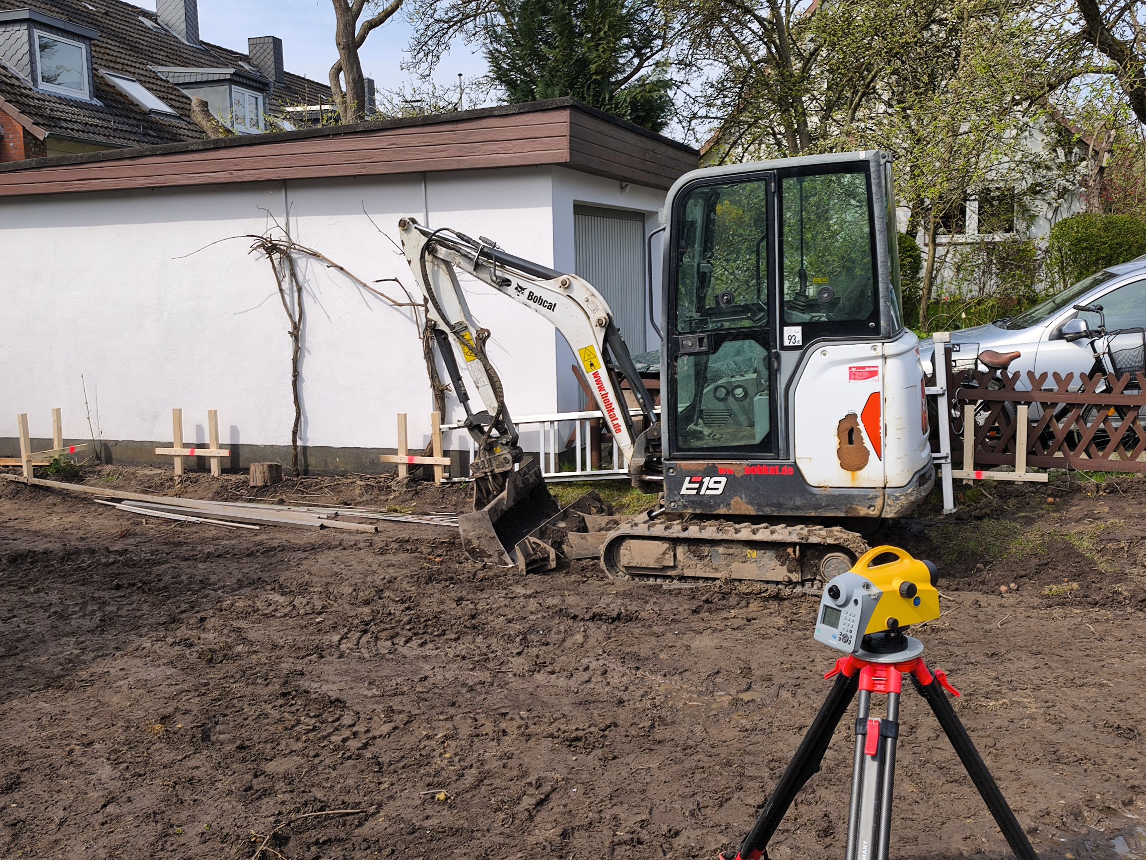 Vermessungstechniker mit Totalstation bei Absteckungsarbeiten auf einer Baustelle – Übertragung des Gebäudegrundrisses in das Gelände